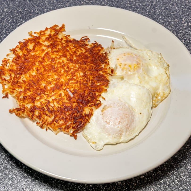 A plate of crispy hash browns and two fried eggs, a classic Umpa's Diner breakfast.