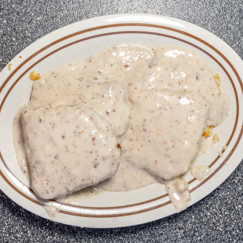 Biscuits and gravy on a white oval plate with brown stripes at Umpa's Diner.
